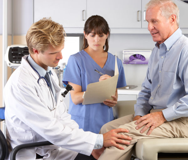 Male Doctor Examining Male Patient With Knee Pain