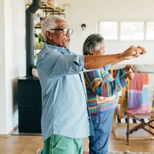 Two older adults doing exercises at home.